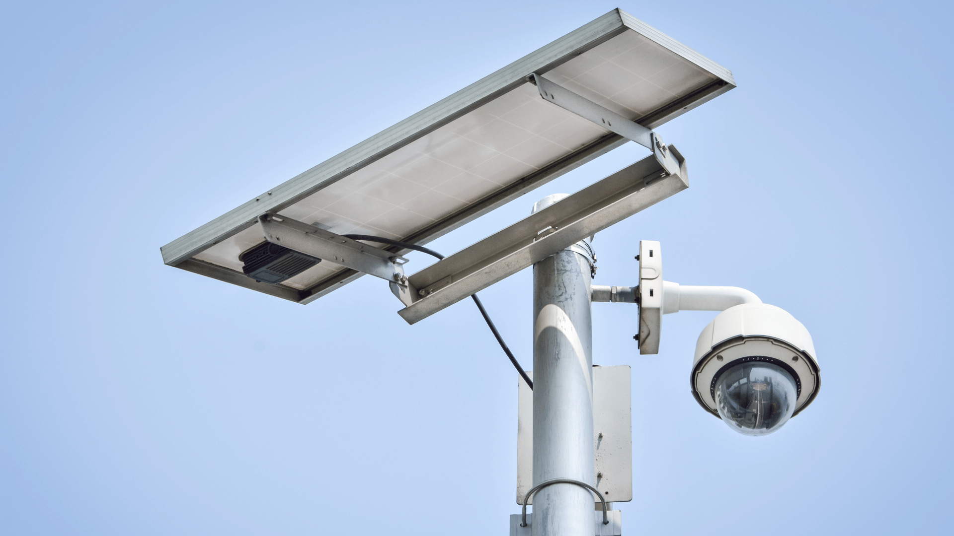 PTZ dome camera and solar panel mounted on pole with sky background