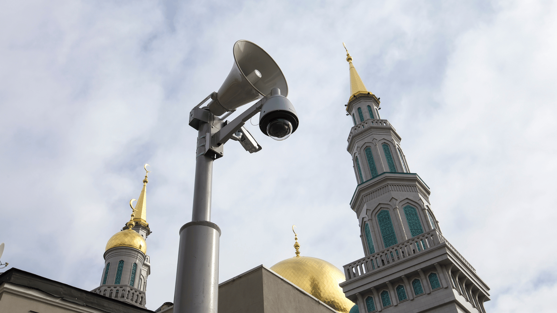 Pole-mounted surveillance camera and loudspeaker system outside a church cathedral