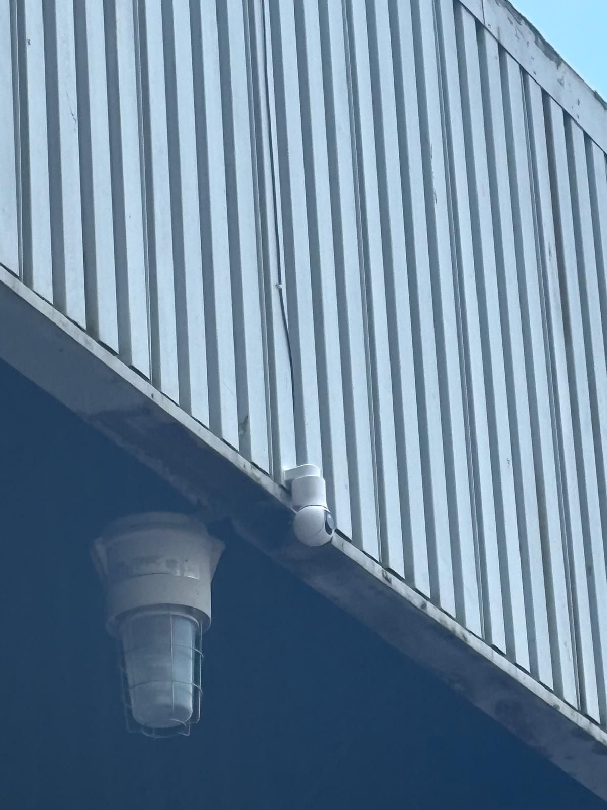 Closeup of Ubiquiti UniFi G6 PTZ camera installed above entrance of grain silo
