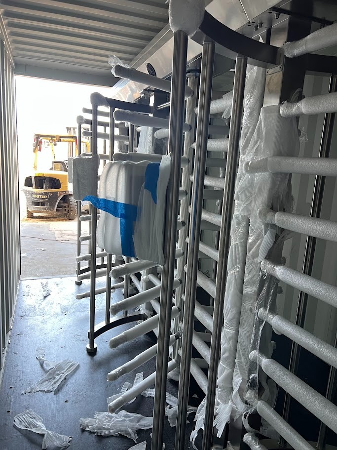 Interior of container security checkpoint during fabrication — multiple full-height turnstiles being installed
