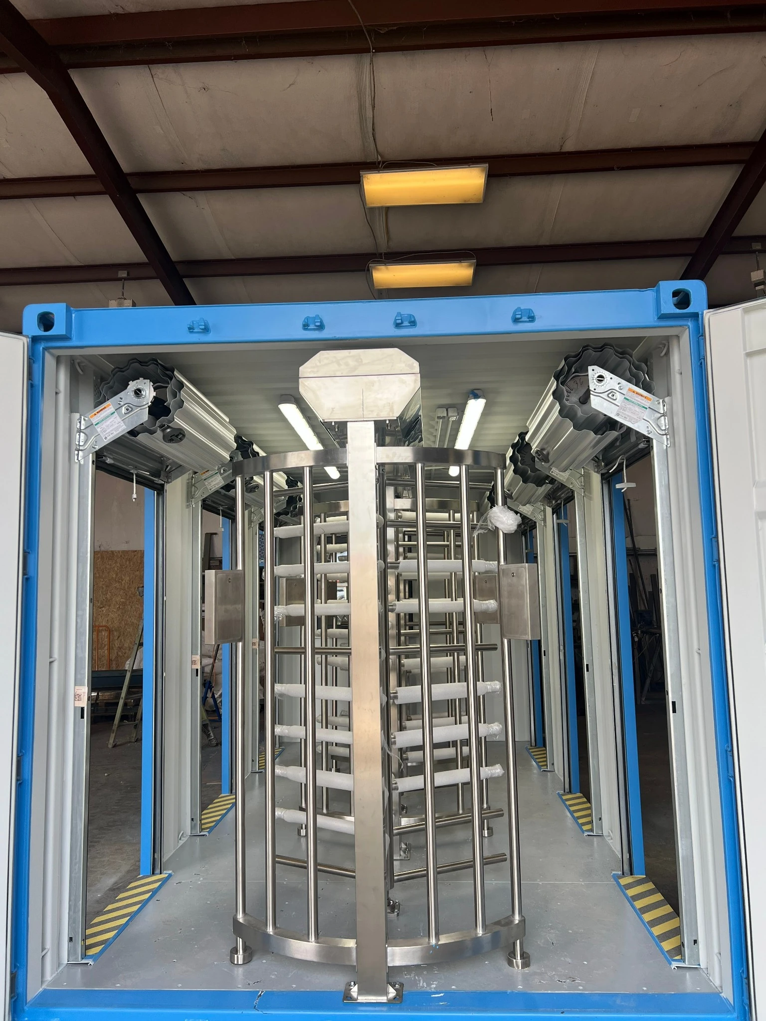 Custom container security checkpoint interior — dual full-height stainless turnstile lanes with LED lighting