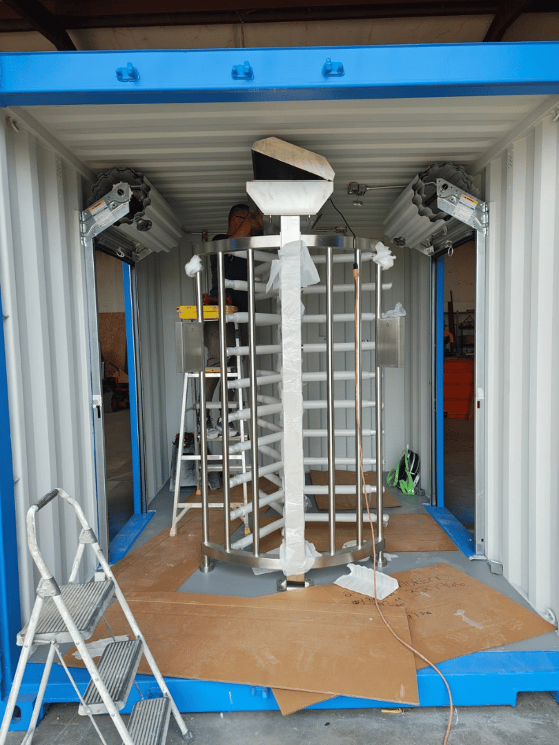 Interior view of a full-height stainless steel turnstile installed inside a 10-ft container security checkpoint